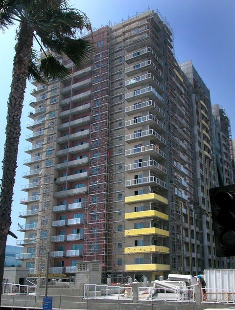 High-rise building under construction, featuring scaffolding and colorful balconies