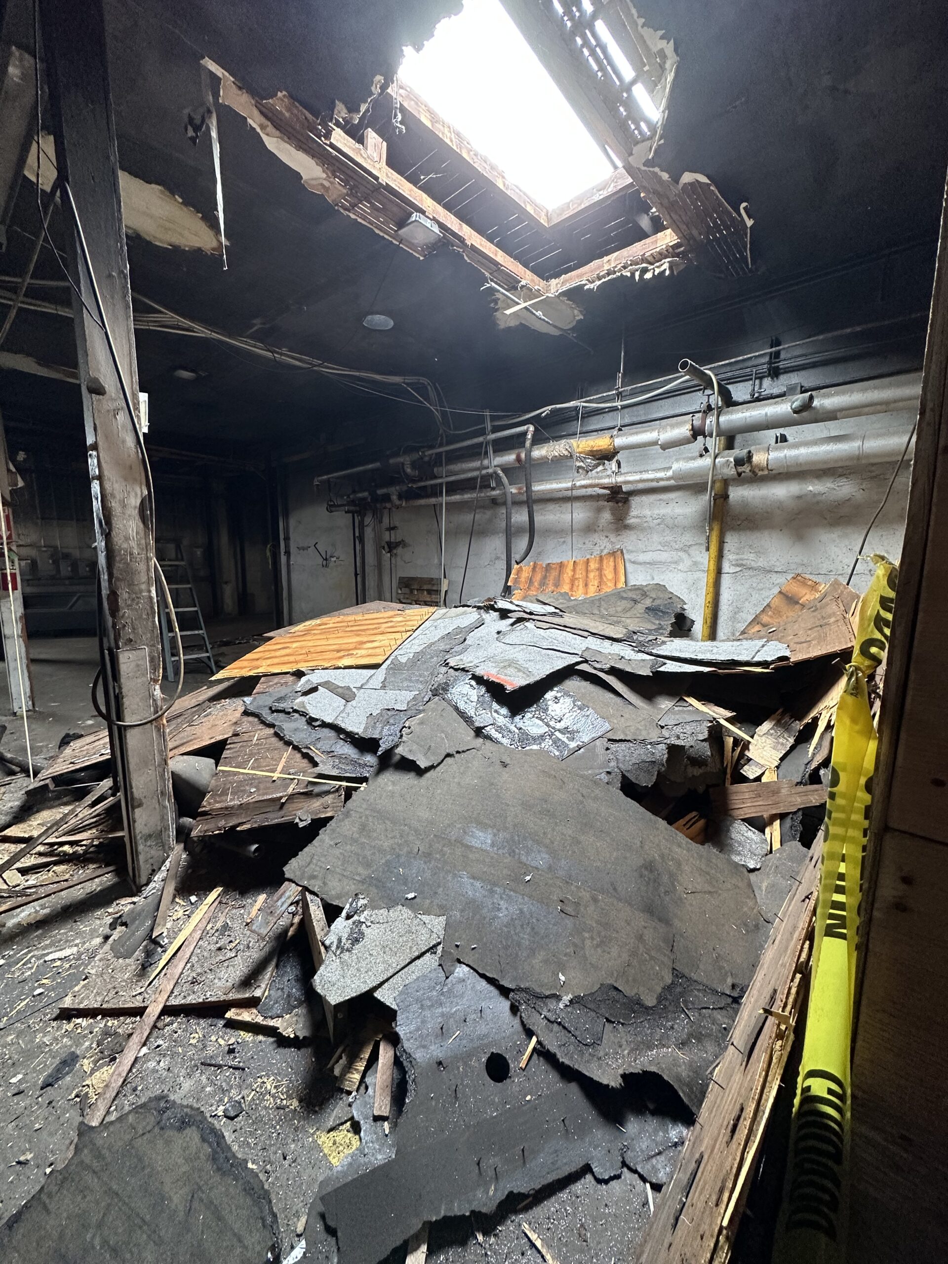 Collapsed debris and exposed beams fill a dimly lit room
